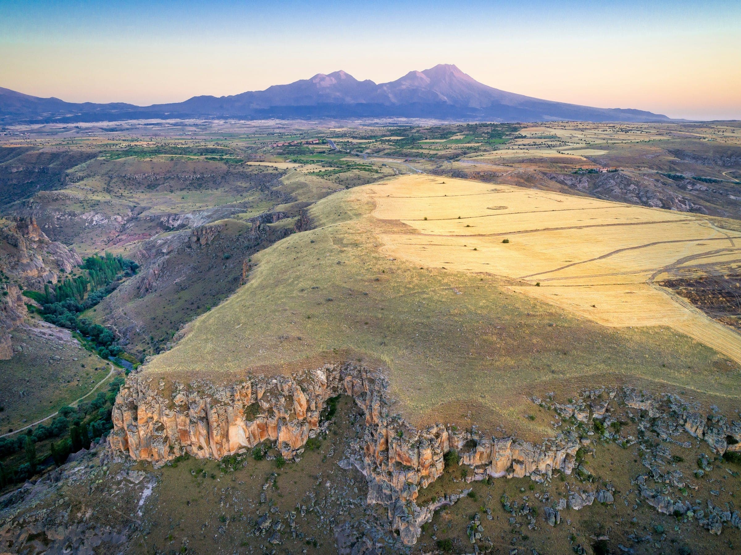 Aerial view of a highland plateau and canyon beneath distant mountains