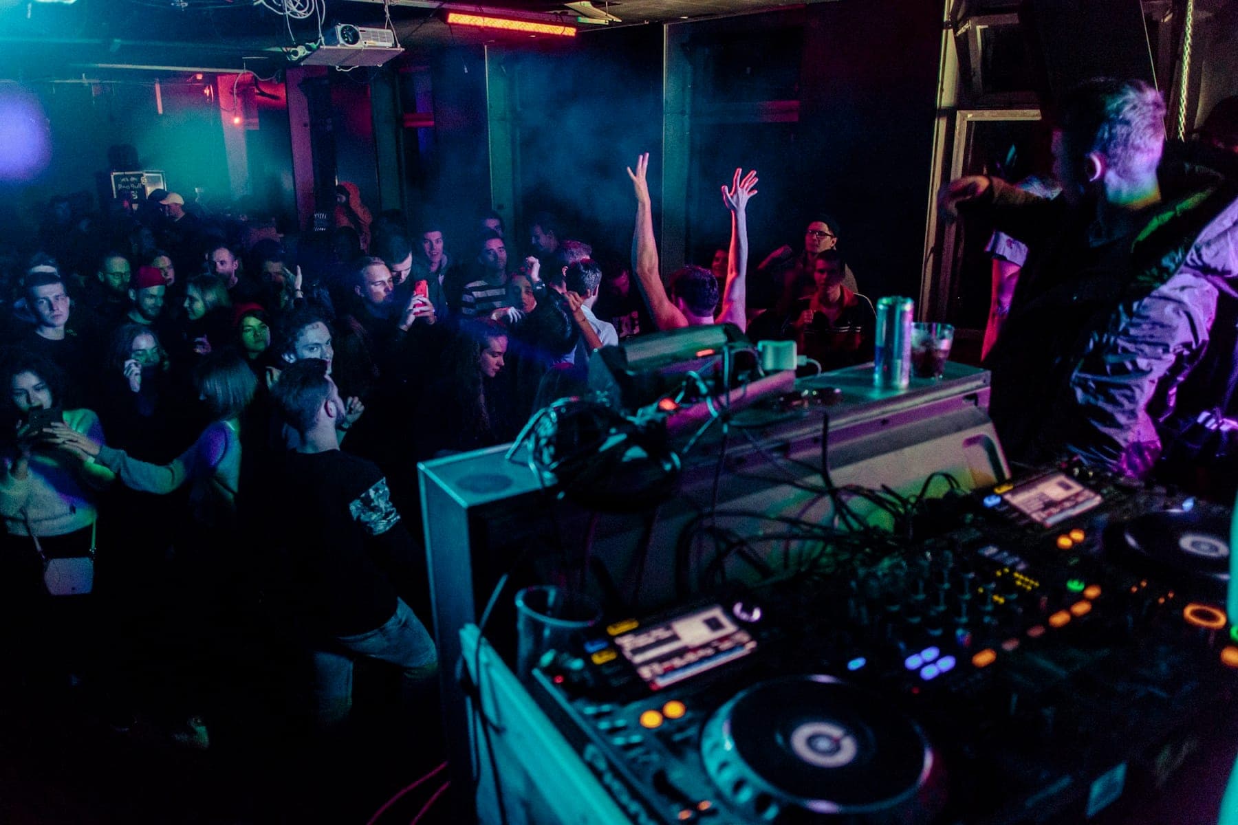 A packed club at night, seen from behind the DJ booth