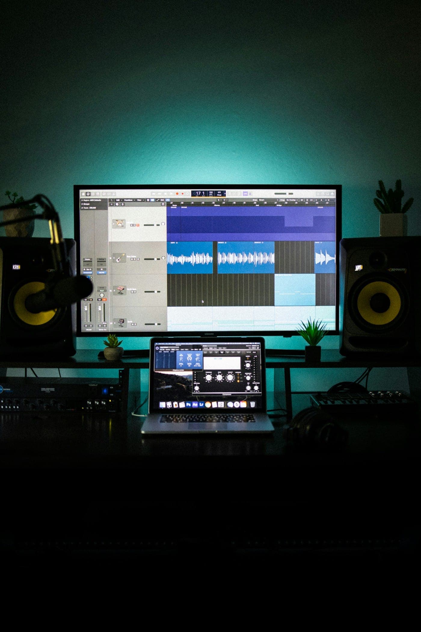 A music production workspace with studio monitors and a session open on screen