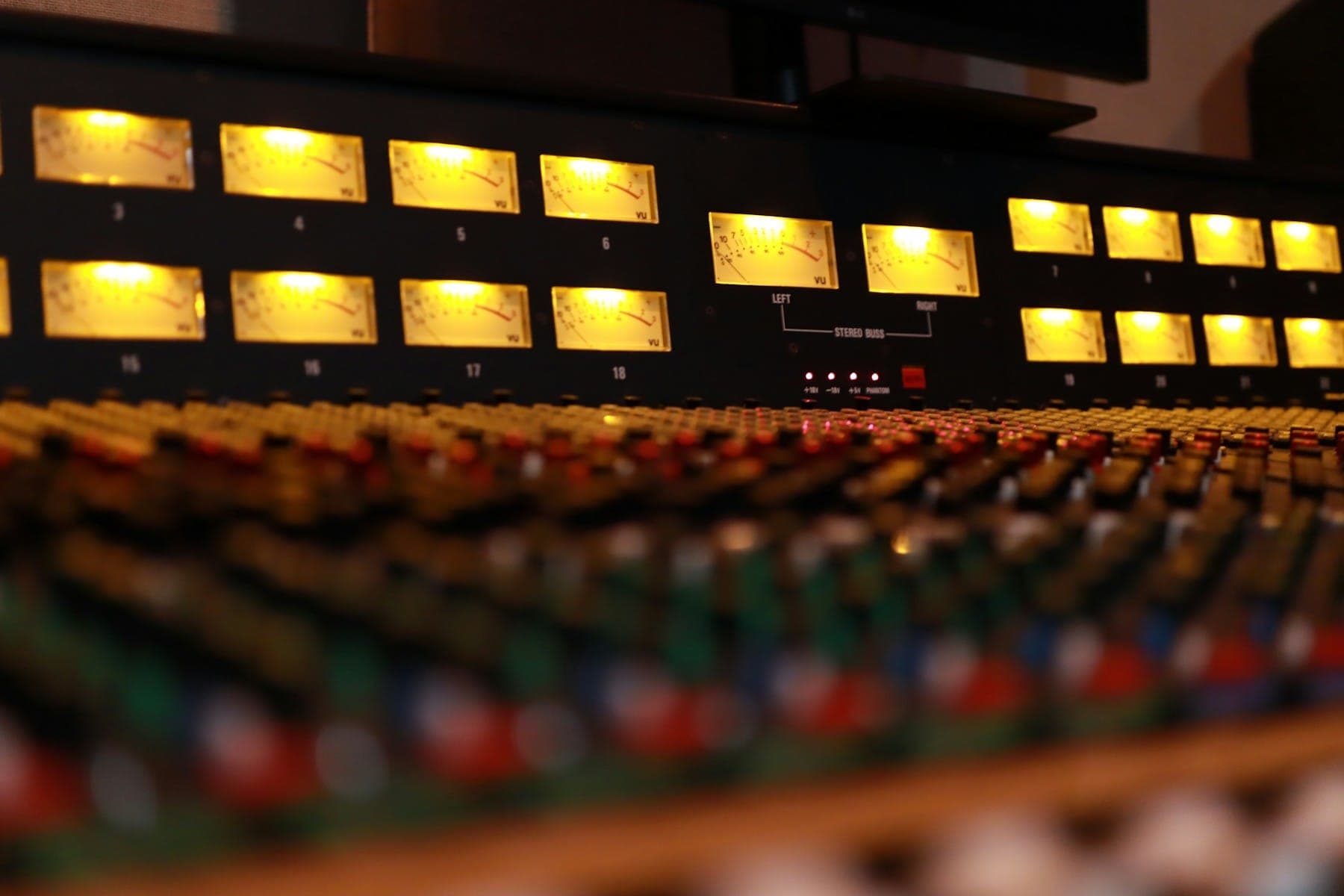 The glowing meters of an analogue mixing console in a recording studio