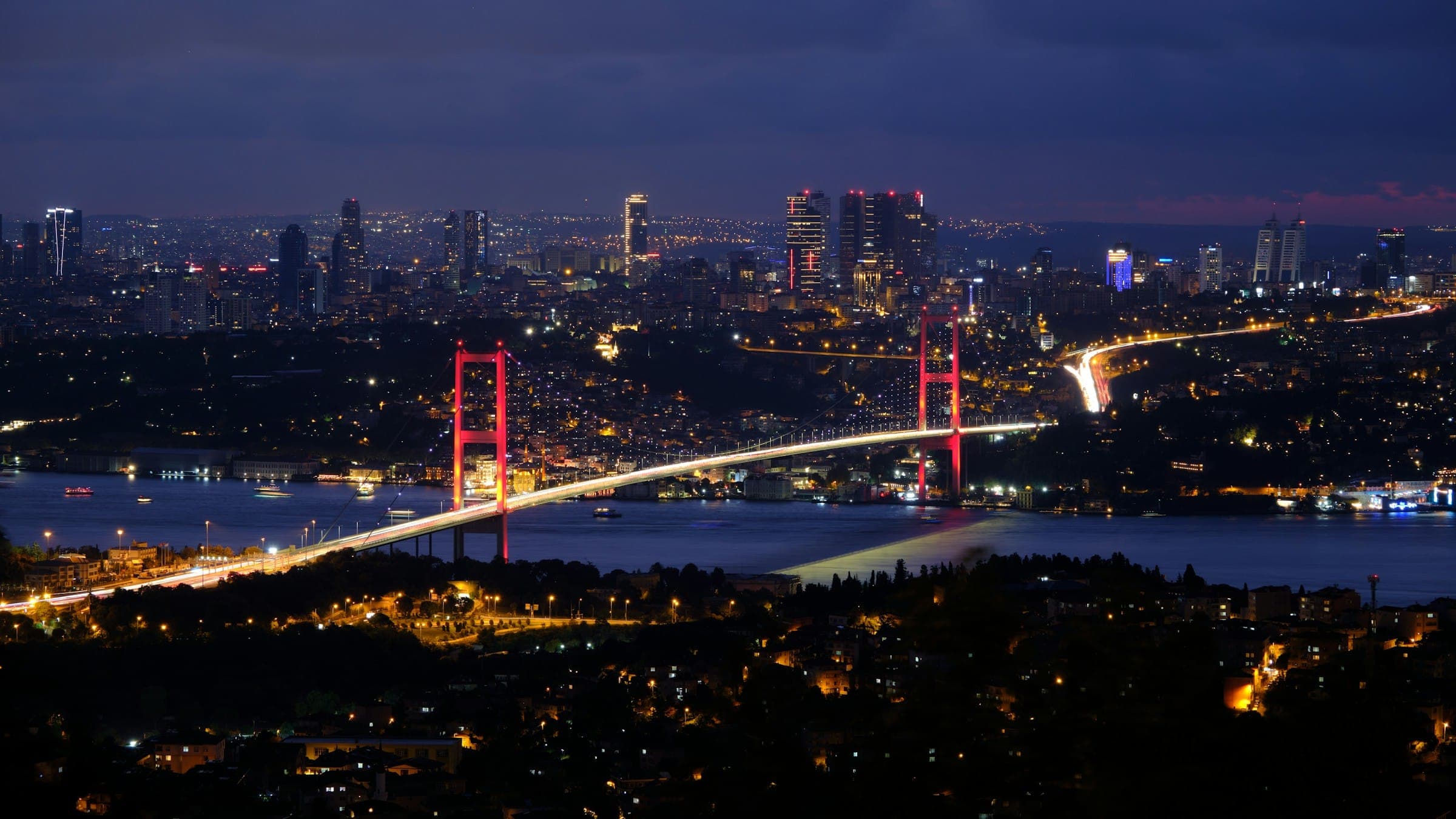 A Bosphorus bridge lit up at night, linking the two sides of Istanbul